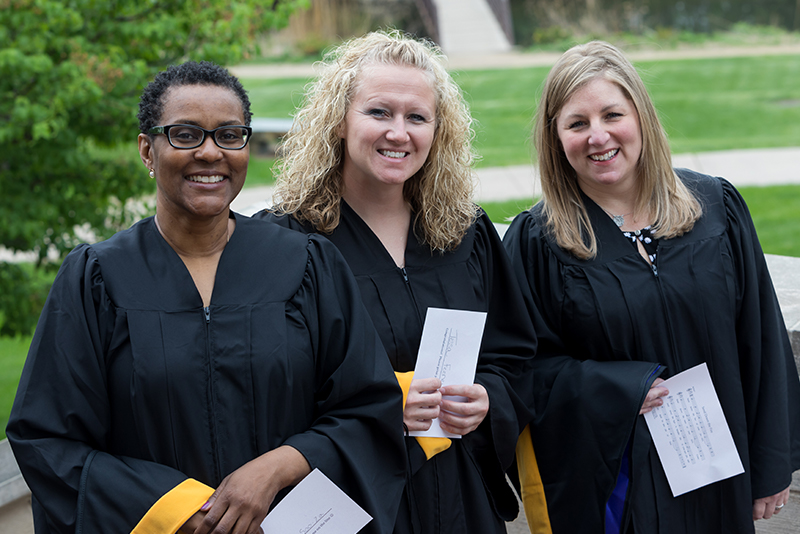 Three College for Adults students in garb at Commencement