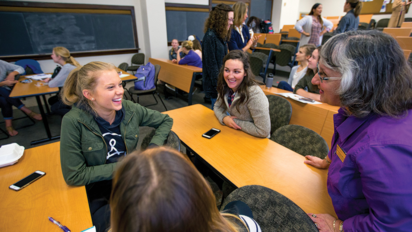 Students talking to teacher in classroom before class