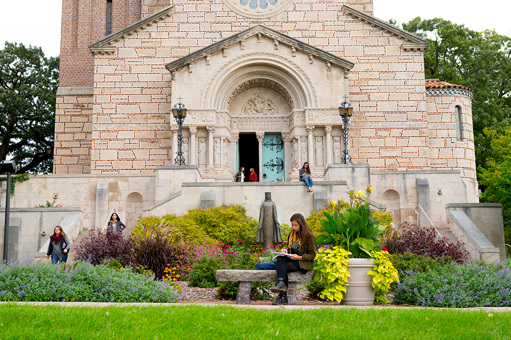 Our Lady of Vicotry Chapel. People are talking by the open door, and studying in the garden in front.