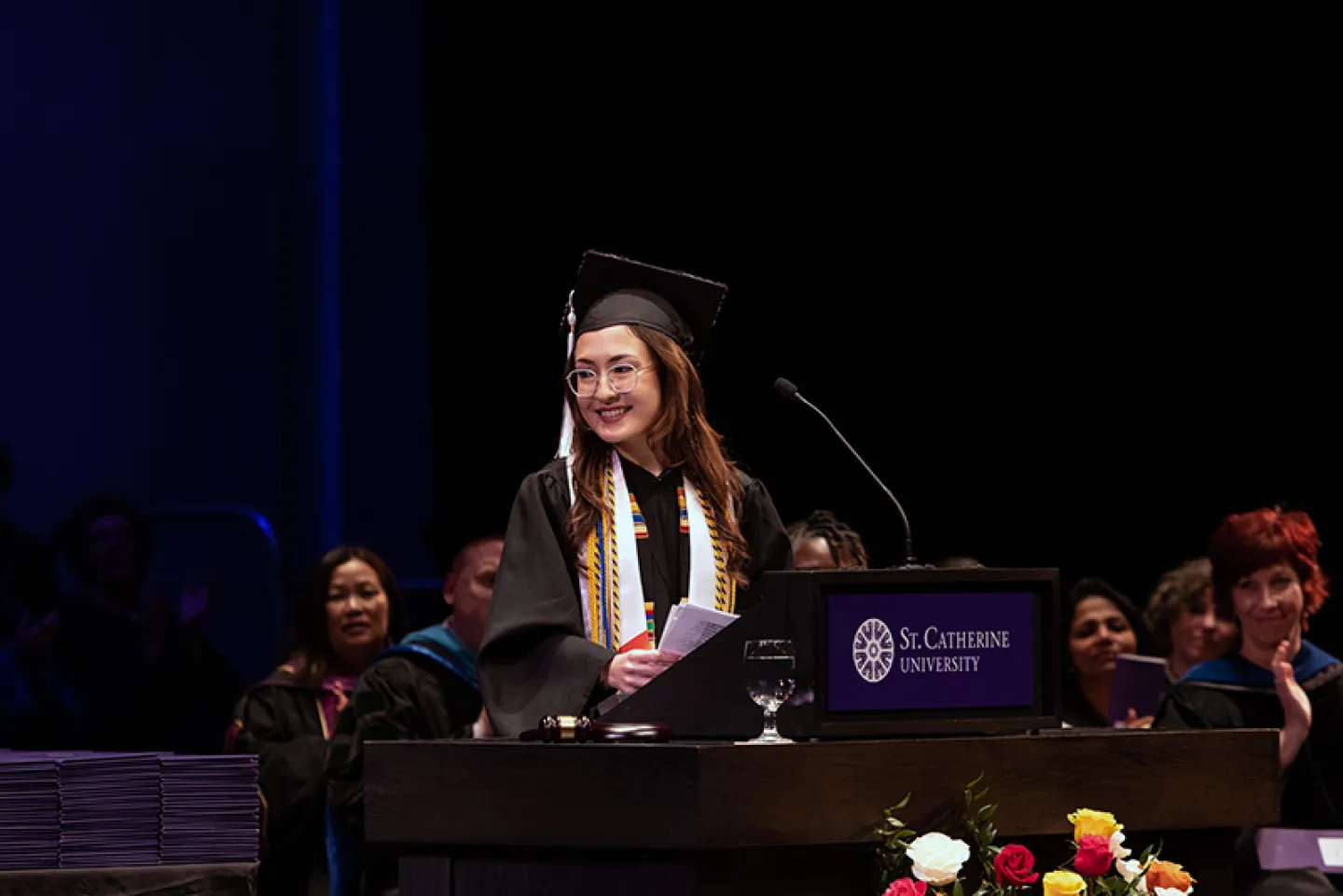 Graduate speaking from podium at graduation ceremony.