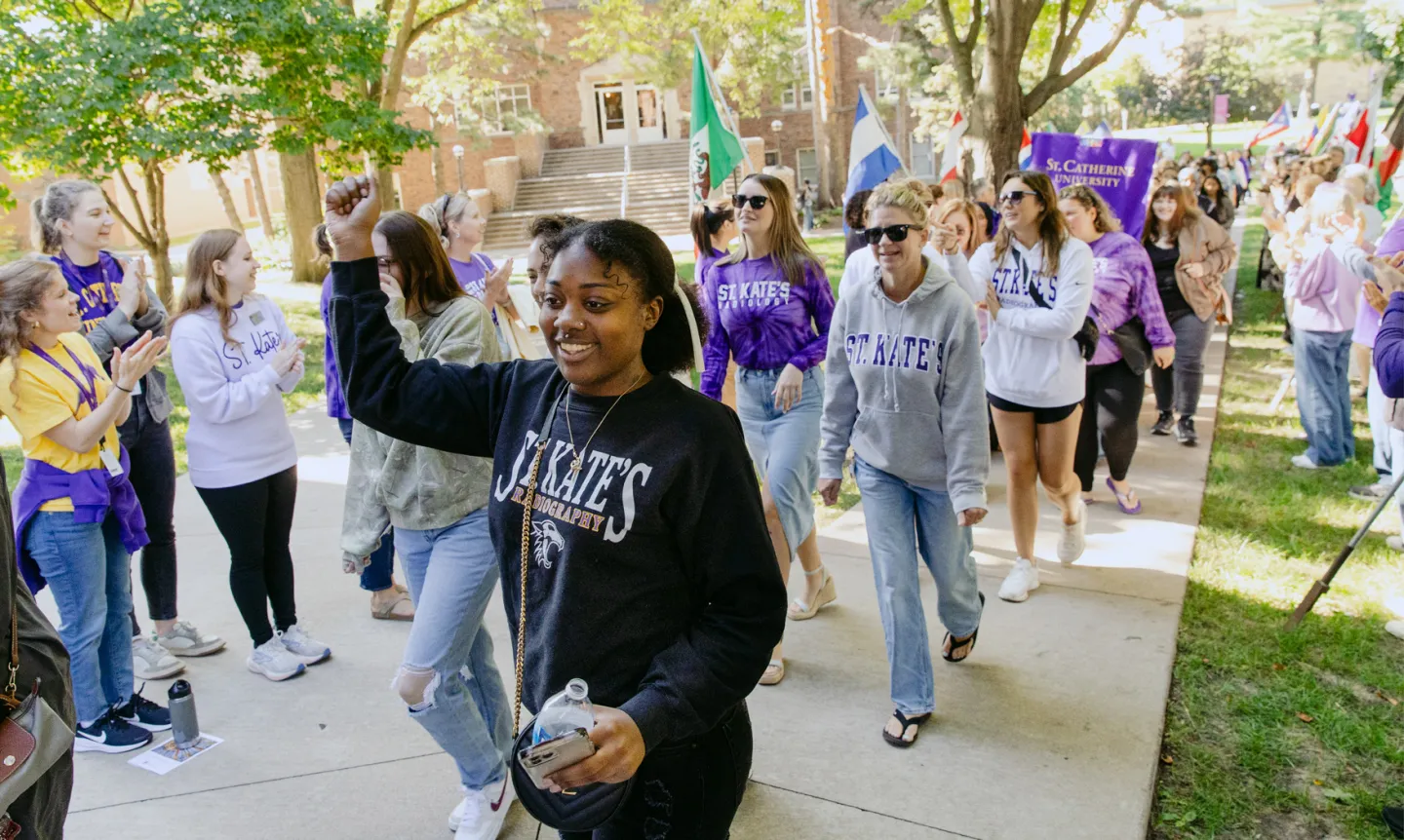 Students smile and cheer as they process across campus.