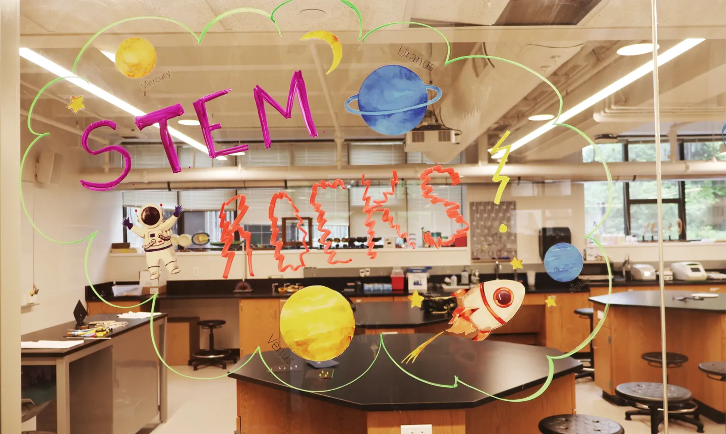 A colorful drawing on glass looking into a lab that reads "STEM rocks!"